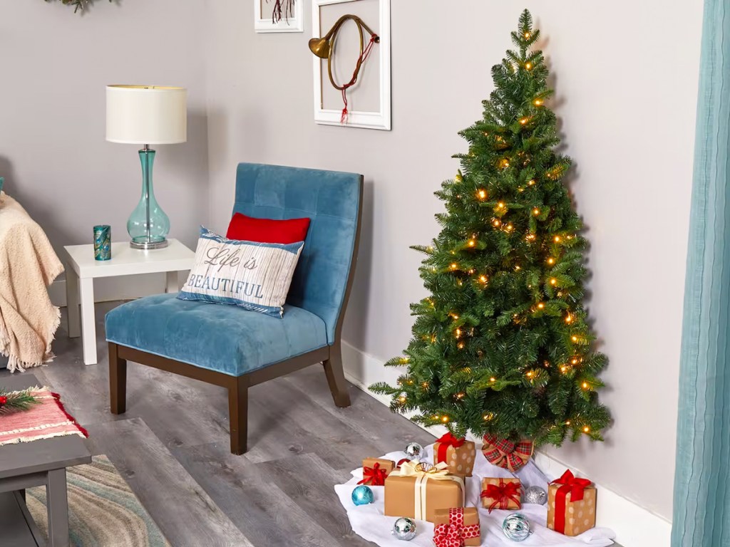 flat back christmas tree with white lights against living room wall