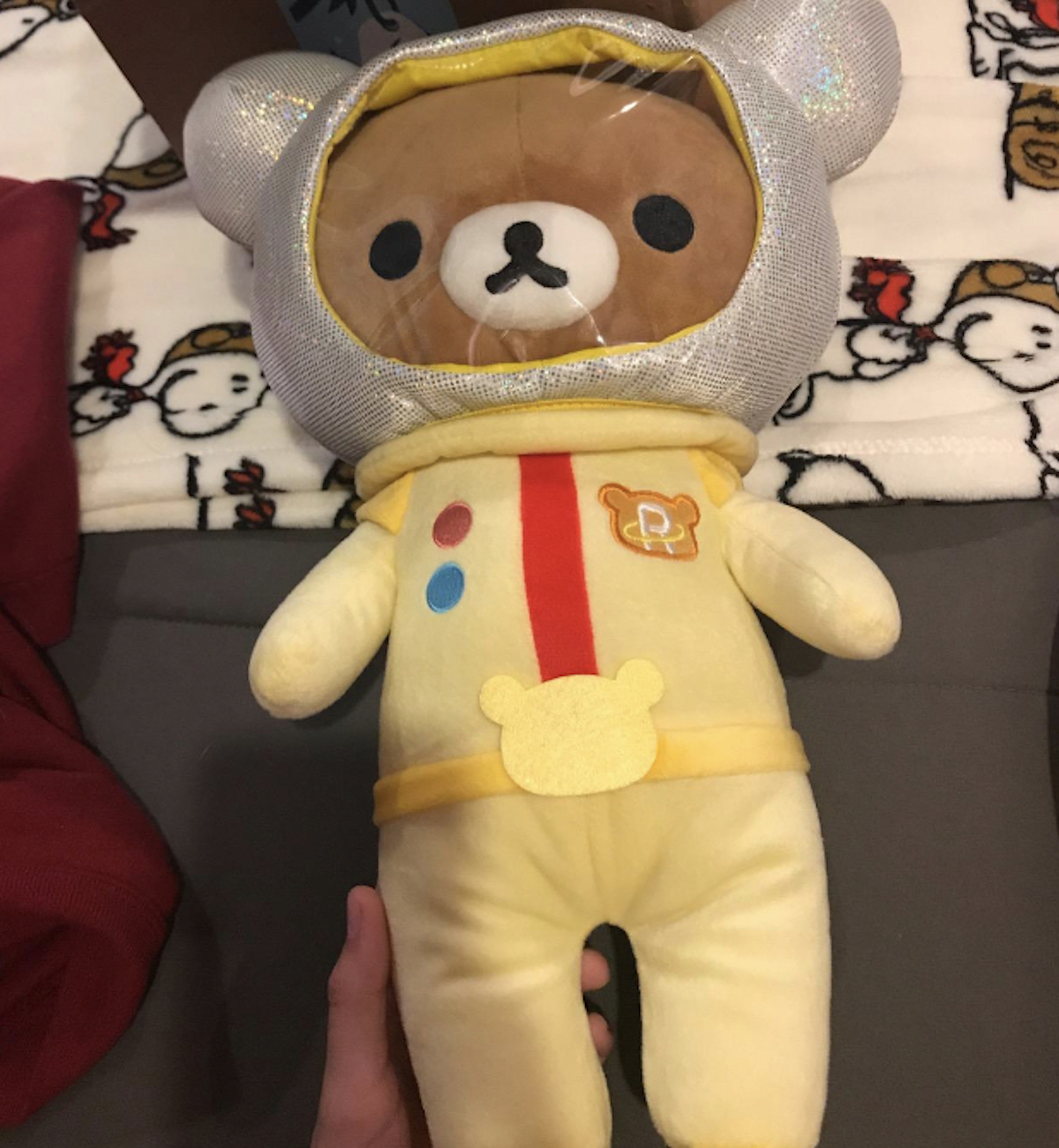 hand holding a yellow San-X Rilakkuma bear on snoopy blanket