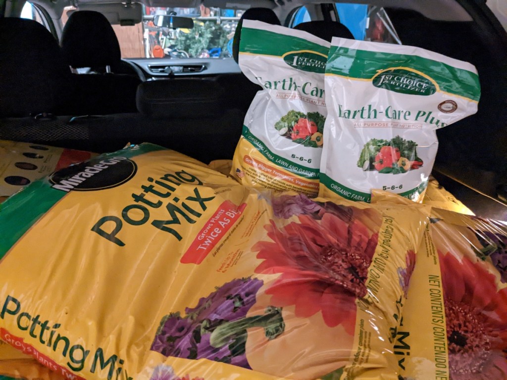 bags of potting soil loaded into the trunk of a car