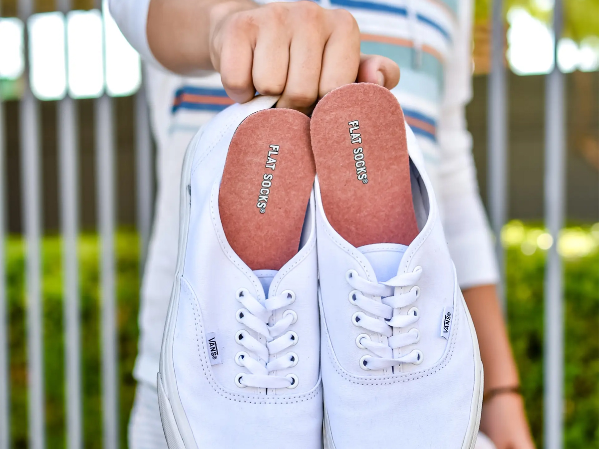 hand holding white shoes with flat socks in them