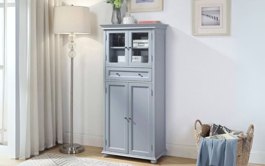 a gray linen cabinet shown with a lam