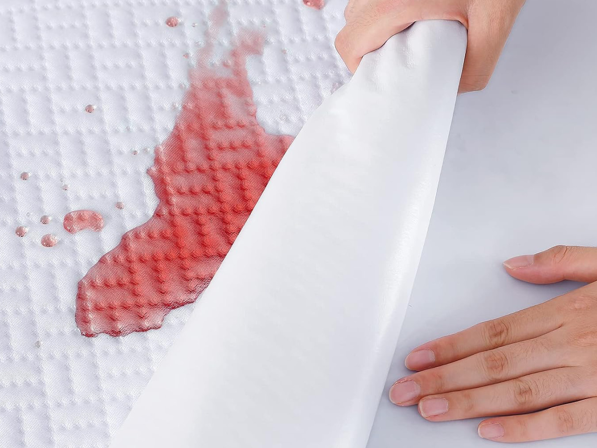 hand removing waterproof mattress protector showing a clean bedding