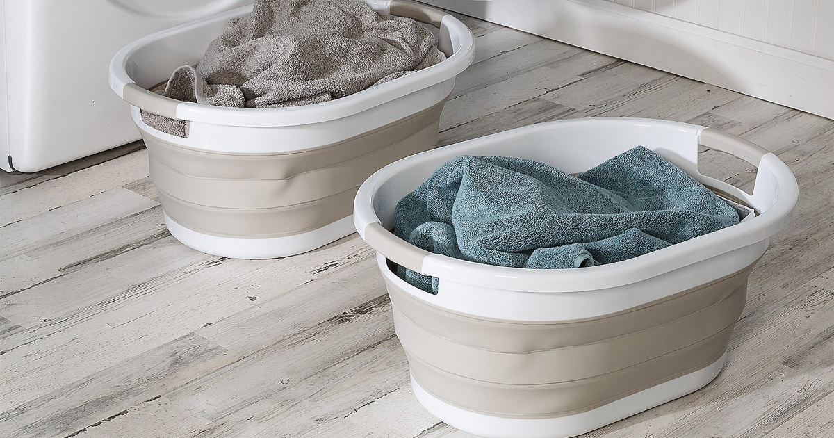 two tan and white collapsible laundry baskets full of laundry sitting on tile floor next to washer