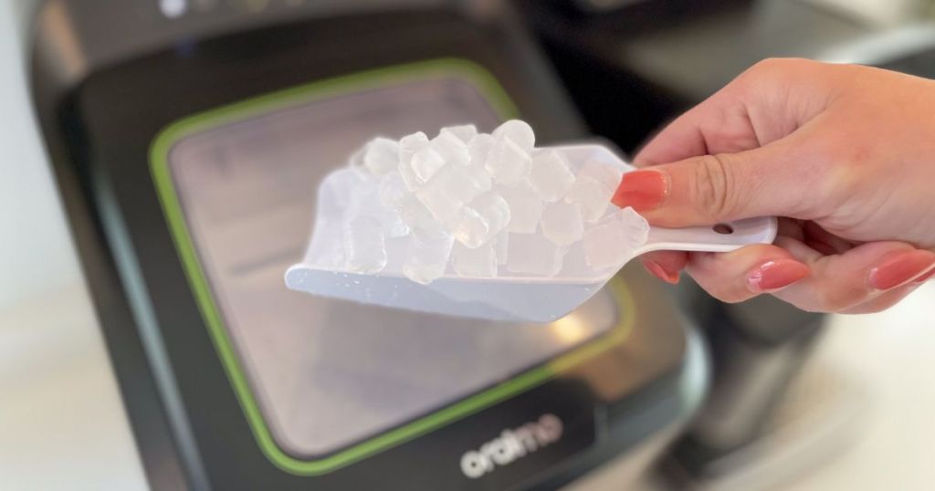 person holding ice scooper filled with ice in front of portable ice machine