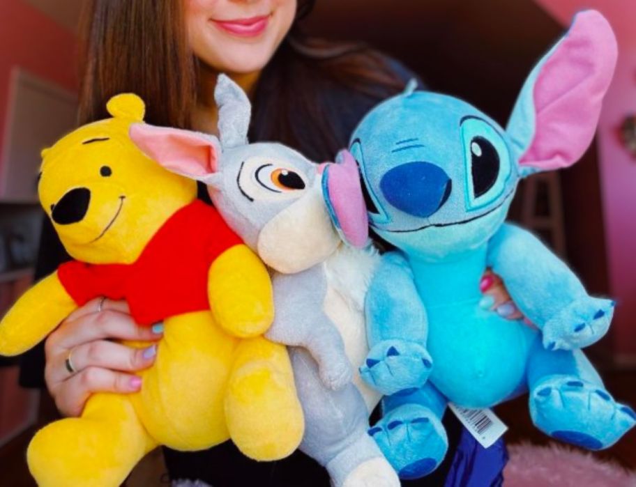 a girl hugging a stitch plush, pooh bear plush, and thumper plush