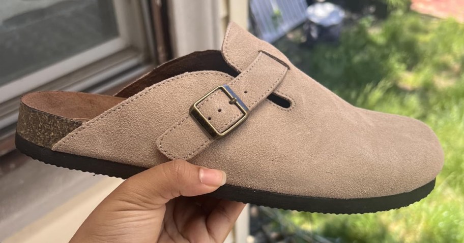 hand holding beige leather clogs