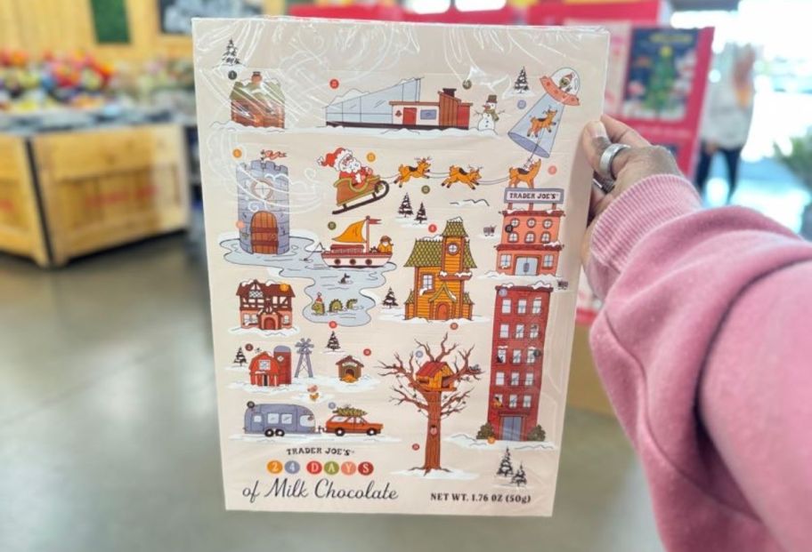 a womans hand holding a trader joes chocolate advent calendar in a store