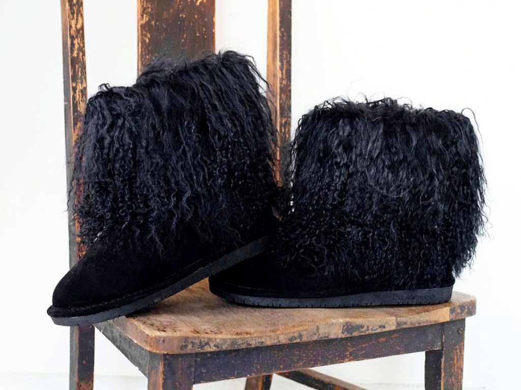 pair of black furry boots on a wood chair