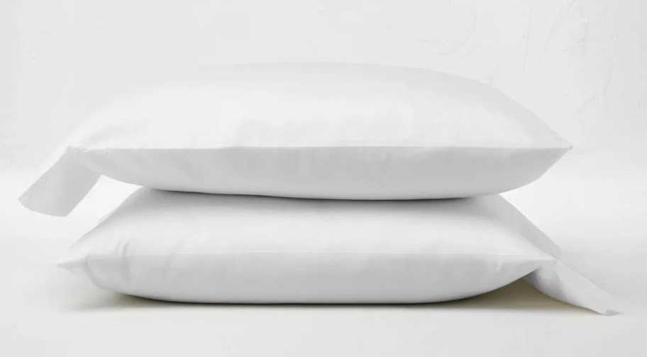 two pillows stacked on top of each other with white pillowcases