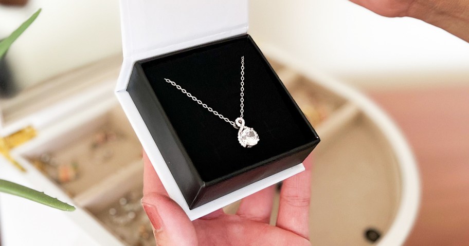 hand holding up pendant necklace in jewelry box