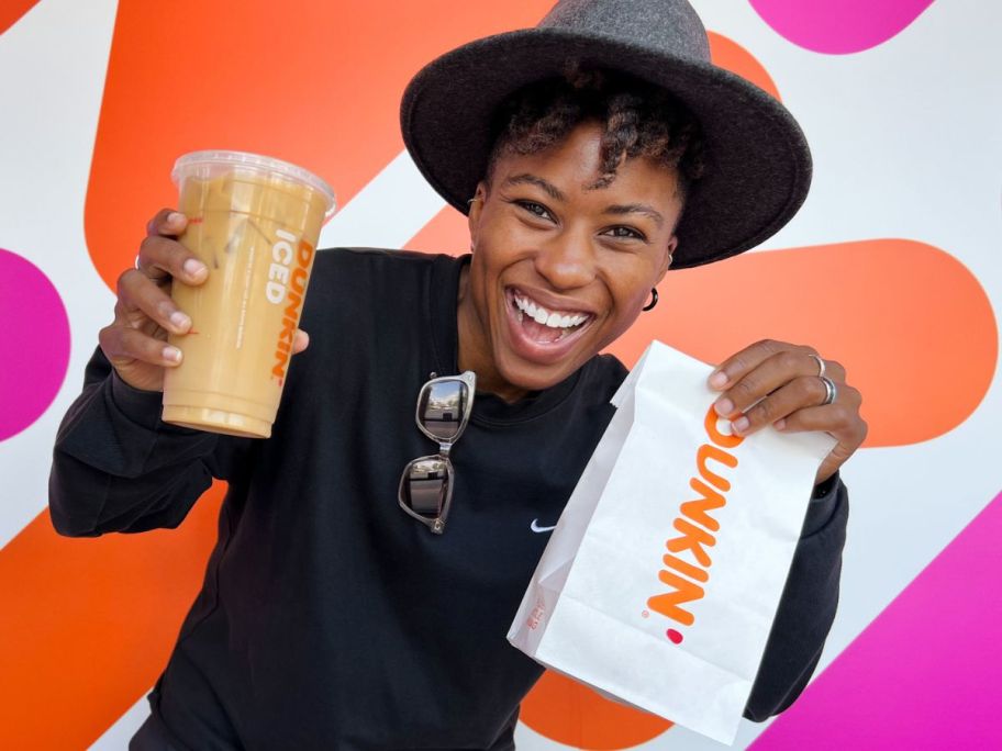 Woman holding a small Dunkin' bag and an iced coffee