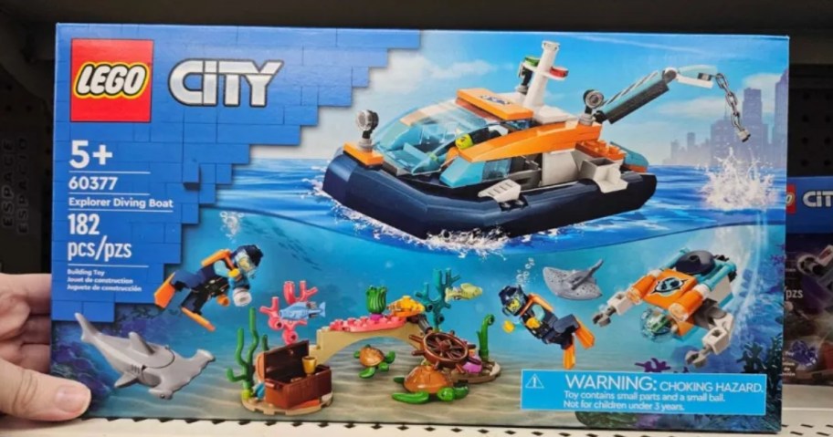 hand reaching for a blue box with an image of LEGO City Explorer Diving Boat Ocean Building Set on it