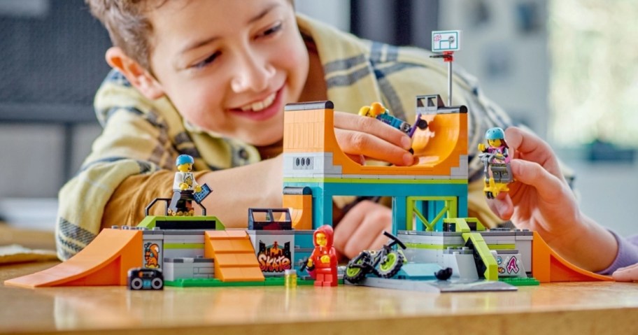 little boy playing with a LEGO set that is a mini skate park with skateboarding figures