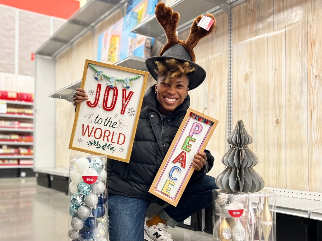 woman holding up christmas decor near ornament sets in store