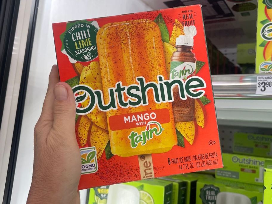 Hand holding a box of Outshine Mango Frozen Fruit Bars with Tajin 
