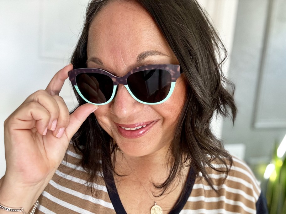 woman touching sunglasses on her face