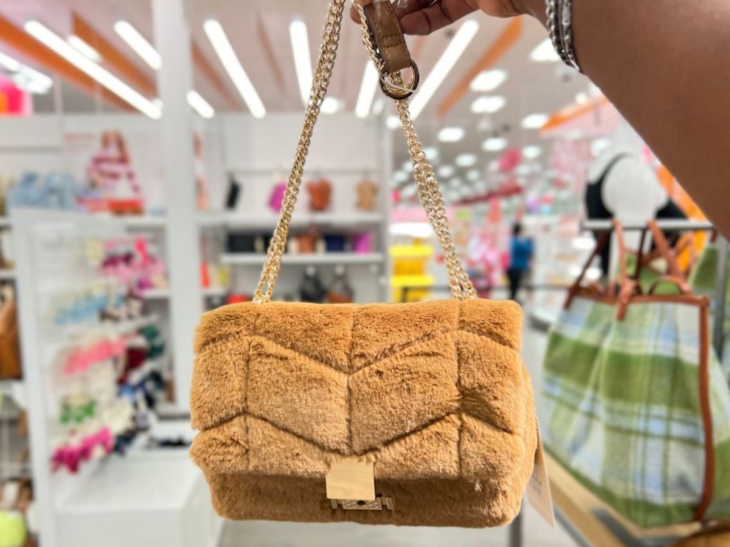 a womans hand displaying A Sophie Crossbody Bag by a new day in brown faux fur