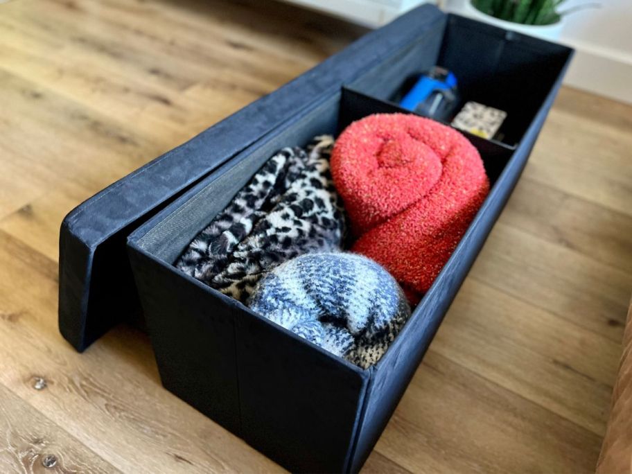 A Sorbus Storage Bench with the lid off shwing blankets and storage inside