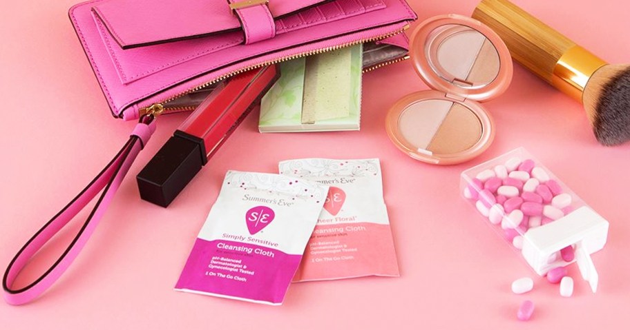 two Summer's Eve Cleansing Cloths onlineing out of pink purse with makeup and mints