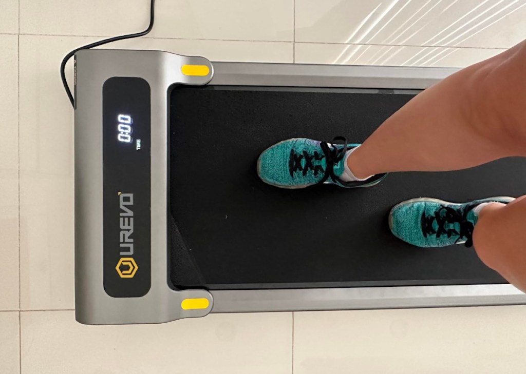 Person wearing blue sneakers walking on under the desk treadmill