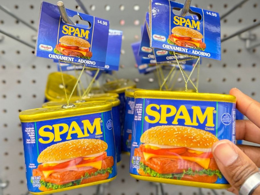 Hand touching Hormel Spam Ornament hanging on a rack at Walmart