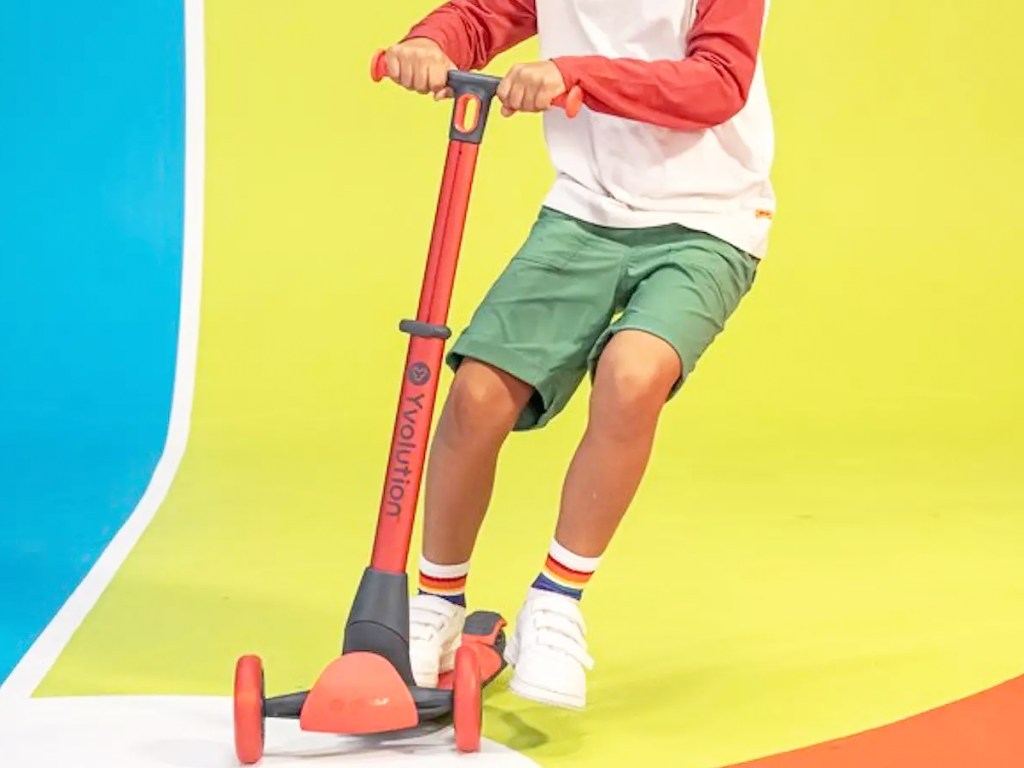 boy riding on a red 3-wheeled scooter