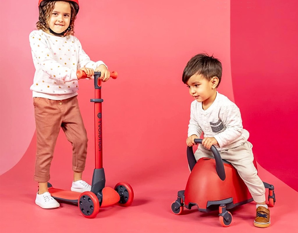 two kids playing on a red scooter and ride-on toy