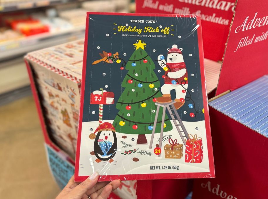 a womans hand holding a trader joes chocolate advent calendar in a store