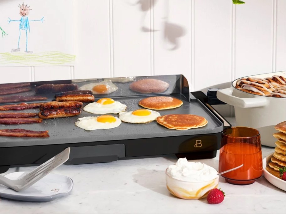 black griddle cooking breakfast food sitting on a counter with other food around it