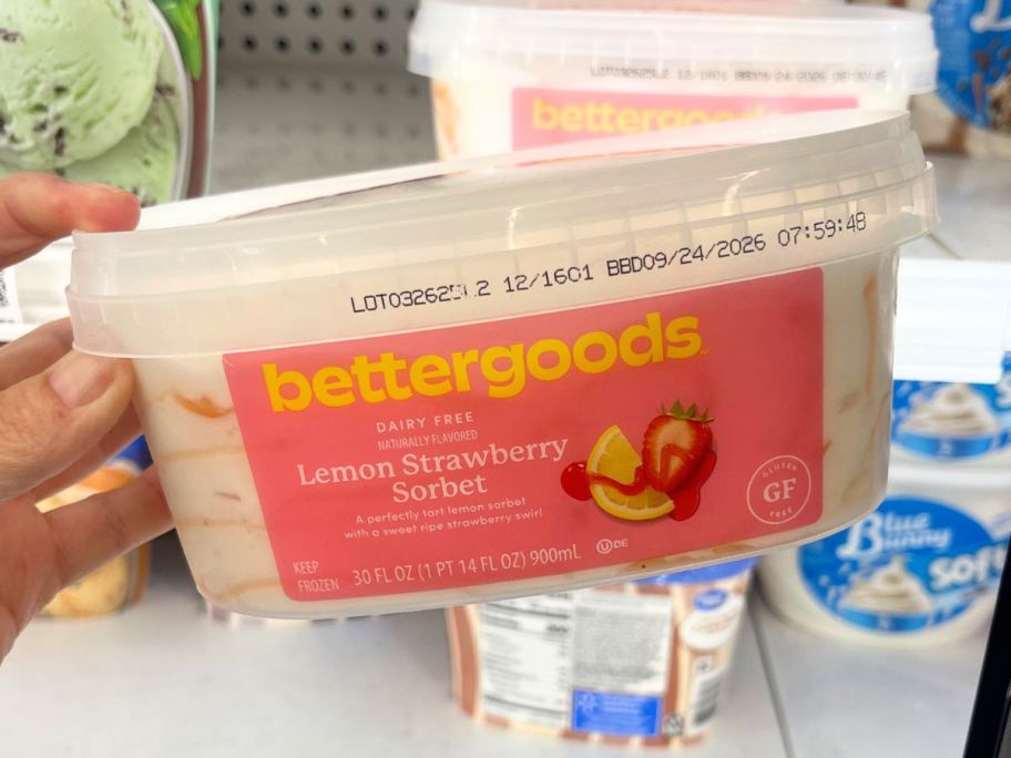 Hand holding a container of Bettergoods Dairy-Free Lemon Strawberry Sorbet