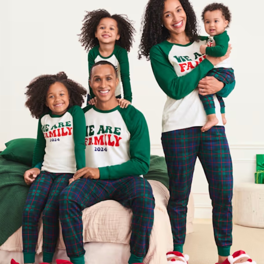 family wearing matching green plaid Christmas pajamas with shirts that say "We are Family"