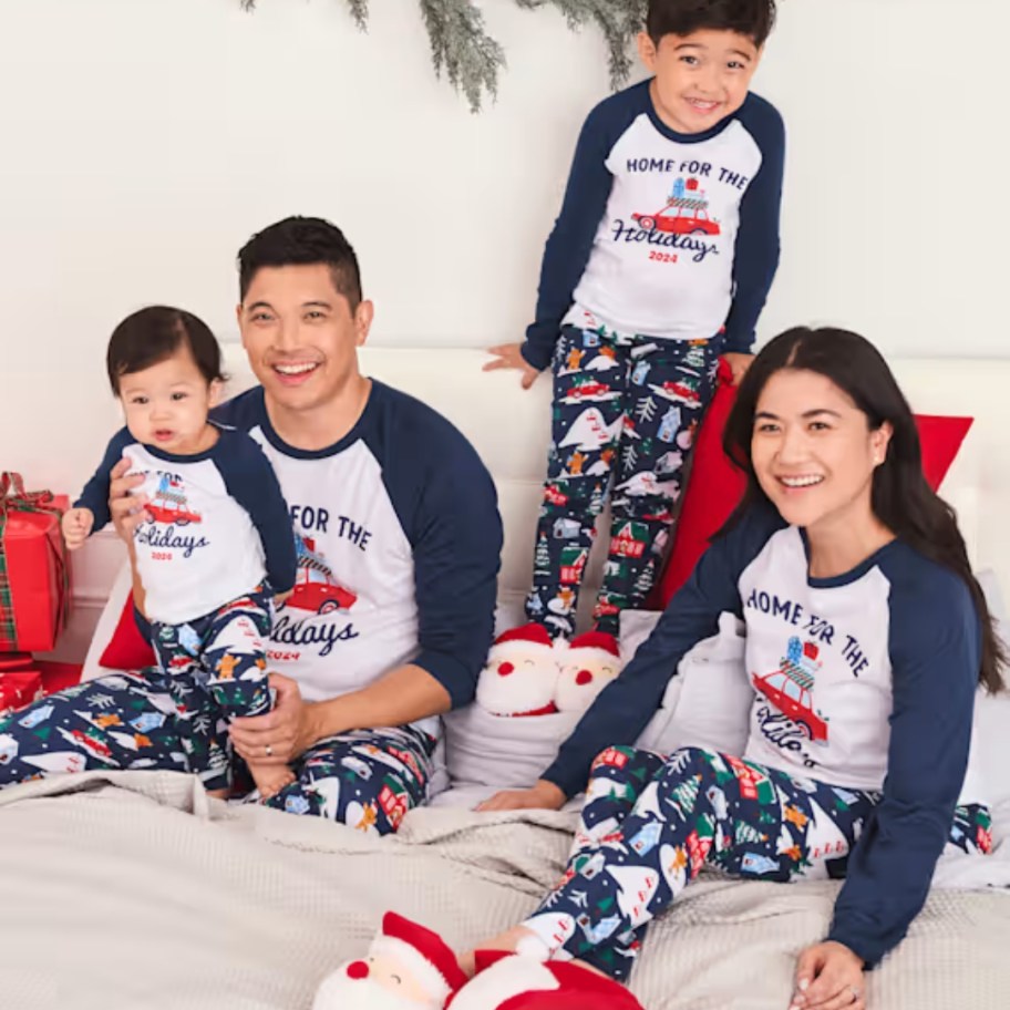 family wearing matching blue, white, red, and green Christmas pajamas with shirts that say "Home for the Holidays"