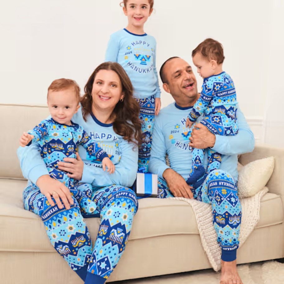 family wearing matching blue Christmas Pajamas that say "Happy Hanukkah" 