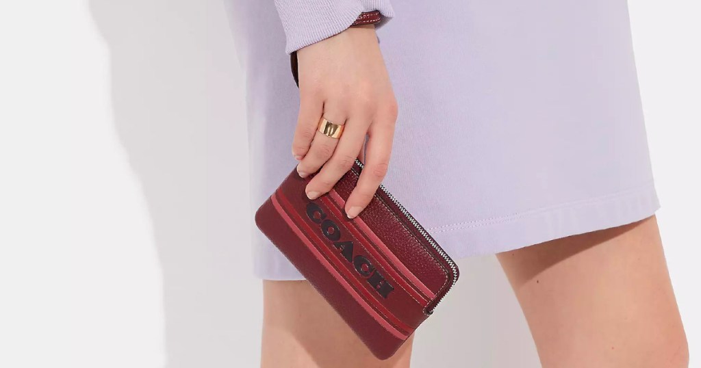 woman in purple dress holding maroon wristlet 