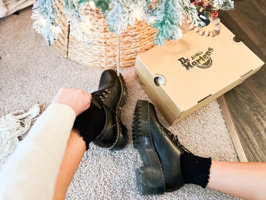 person wearing dr martens next to shoe box under christmas tree