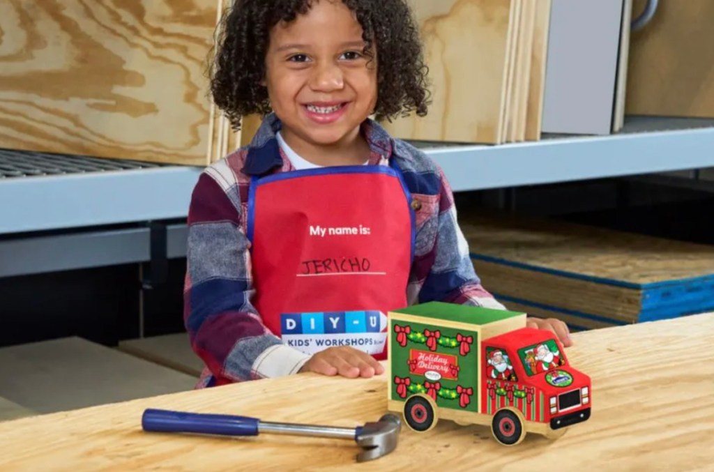 boy sitting at plywood table with diy holiday truck and hammer