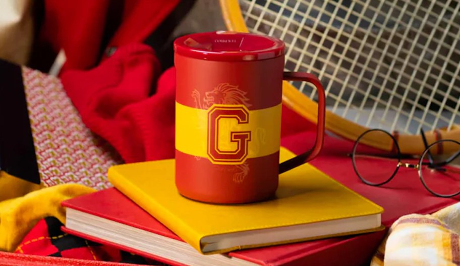 red and yellow harry potter themed corkcicle mug on yellow book