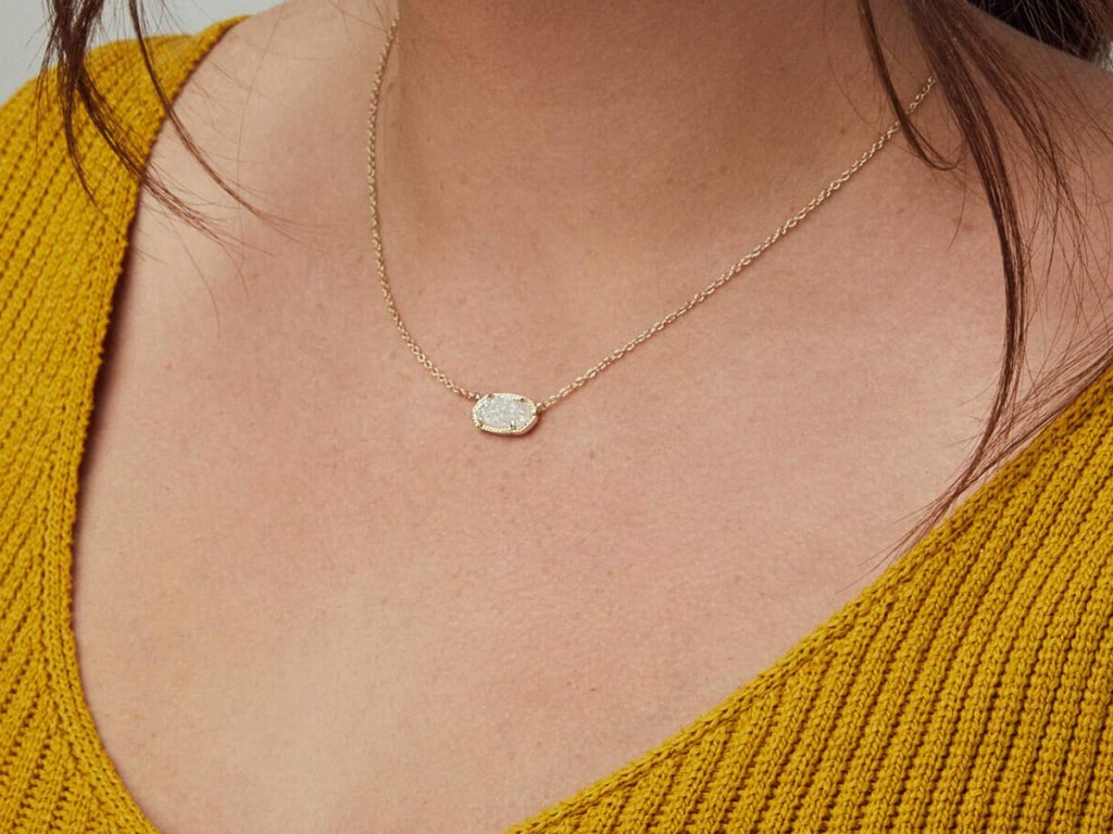 closeup of delicate necklace on a woman with a mustard-colored shirt