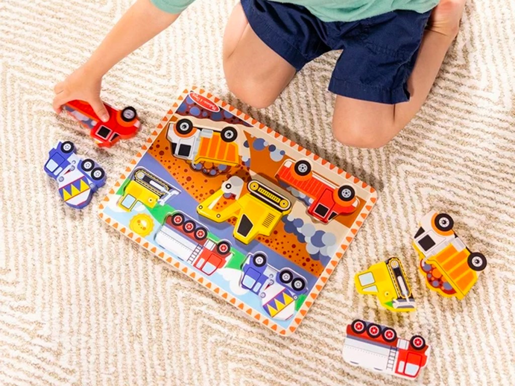 kid putting vehicle puzzle together on floor