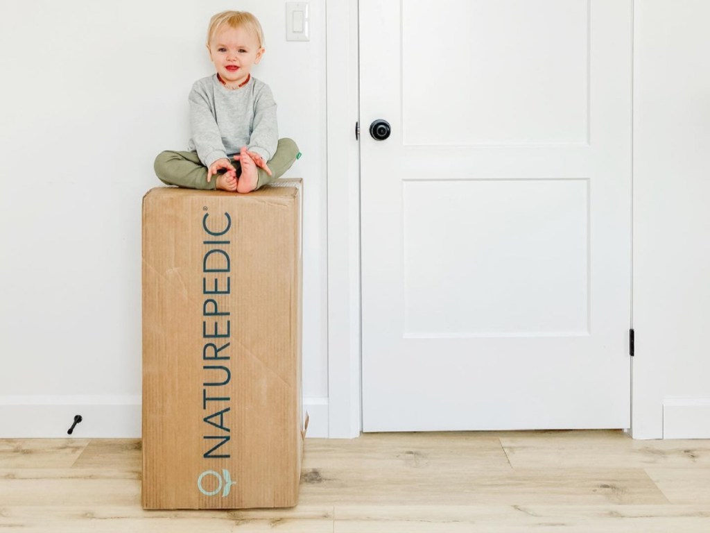 baby sitting on top of mattress box