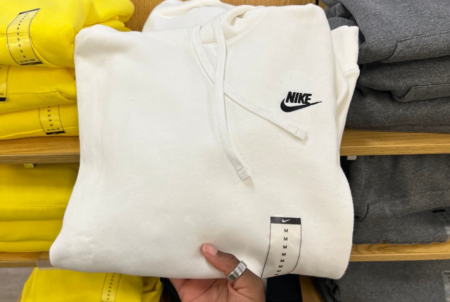 hand taking white nike hoodie off of shelf