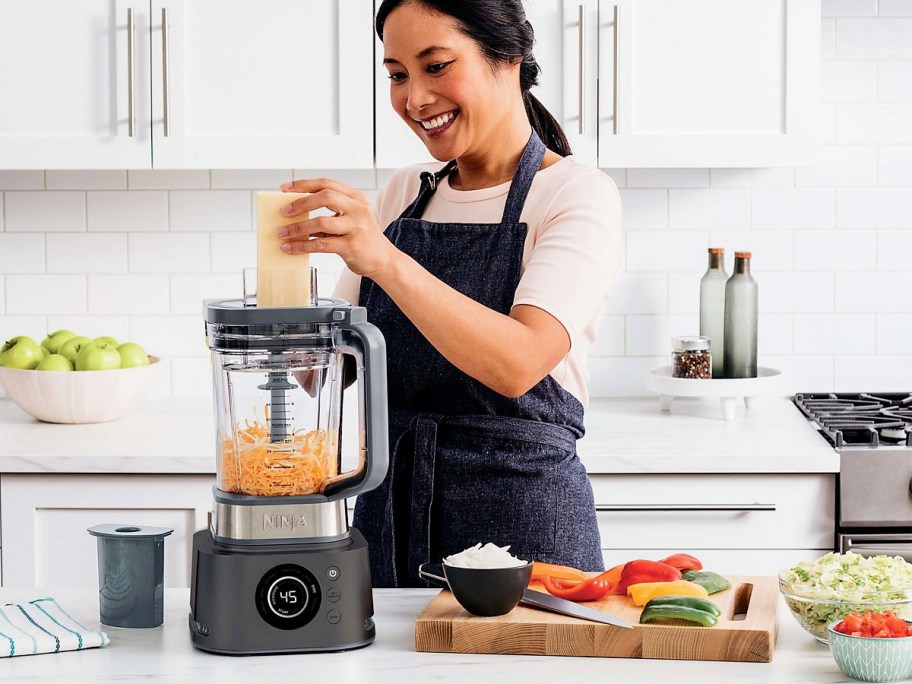 woman using a tamper with a ninja foodi blender system