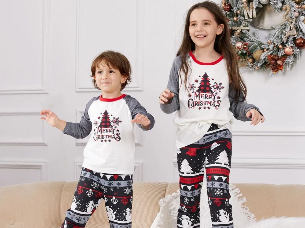 boy and girl wearing matching pajamas standing on couch