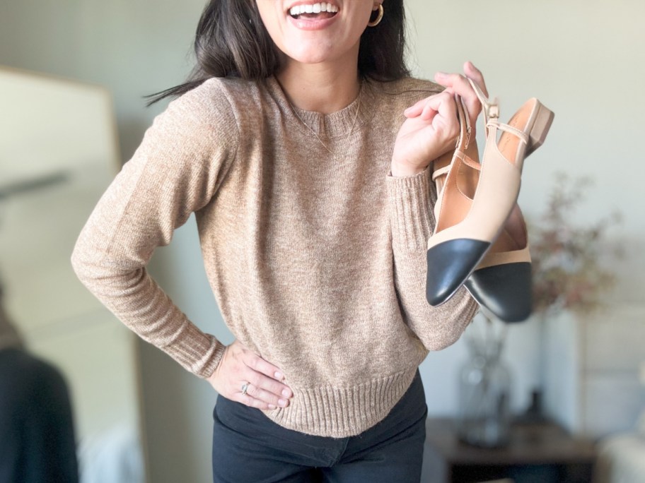 woman in tan sweater holding shoes