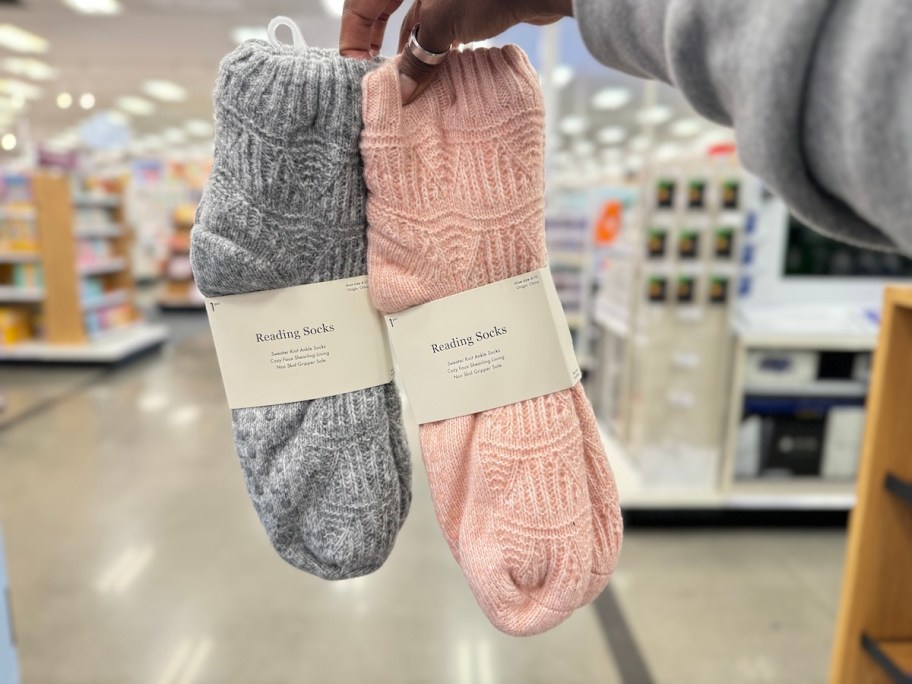 hand holding a pair of gray and pink reading socks