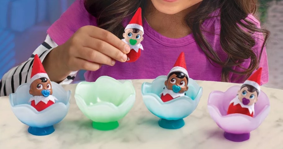 little girl playing with 4 different Elf on The Shelf Frost Pips Mini Blooms