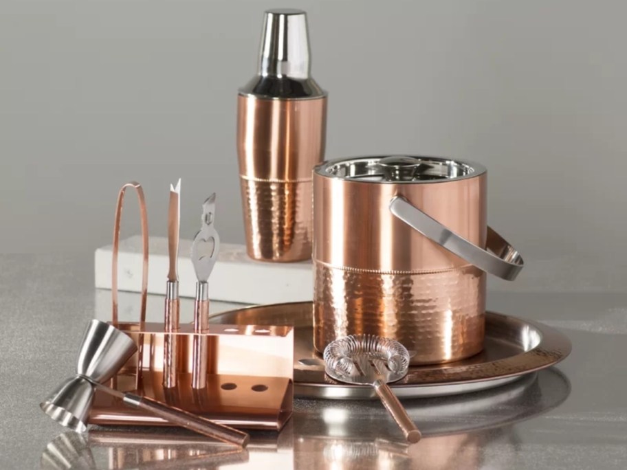 a copper bar set with an ice bucket, shaker, and other bar tools