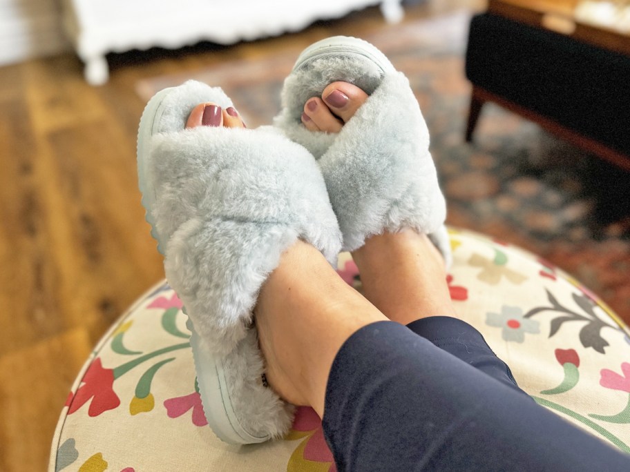 woman wearing light blue slippers with feet up on floral print ottoman