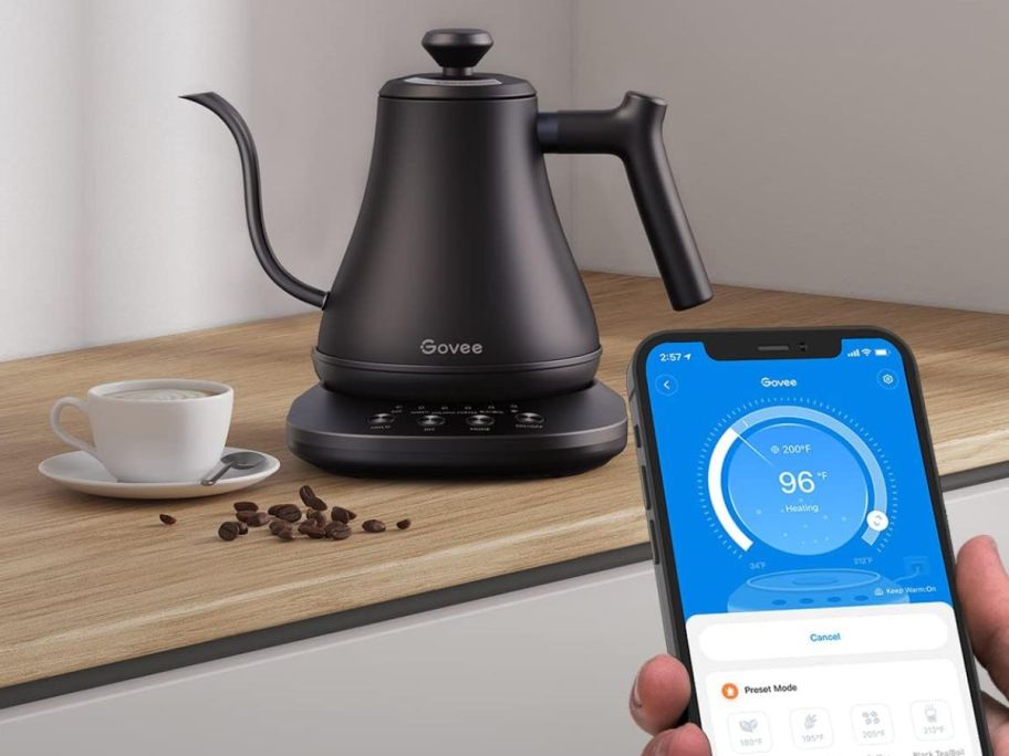 hand using a smart phone to control a Govee Smart Kettle in the background