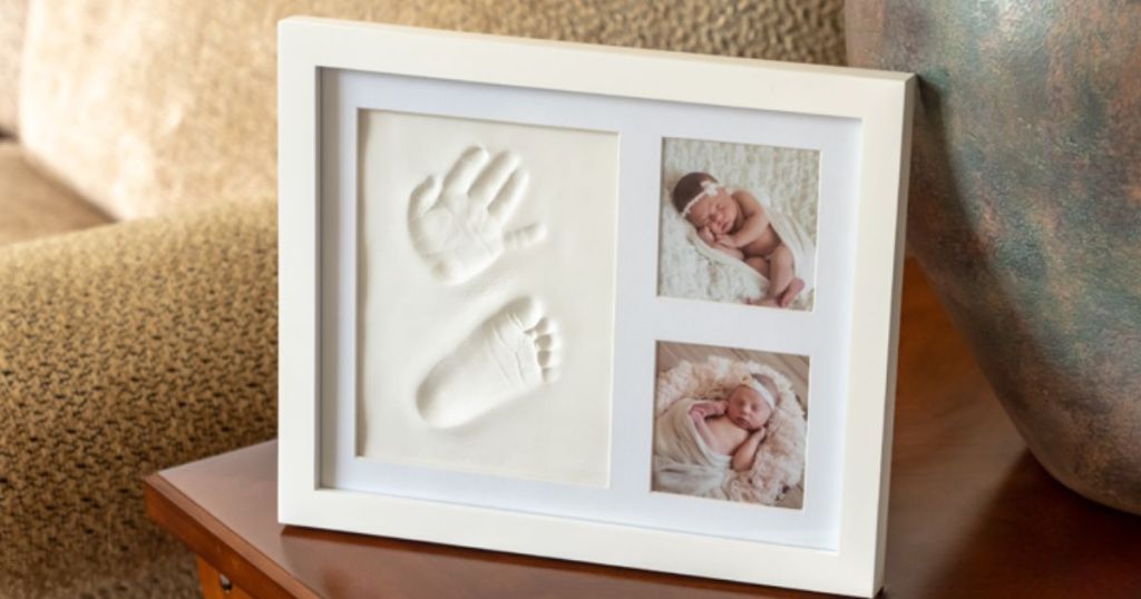 Little Hippo Baby Handprint & Footprint Kit w/ Photo Frame in White shown sitting on a side table in a living room 